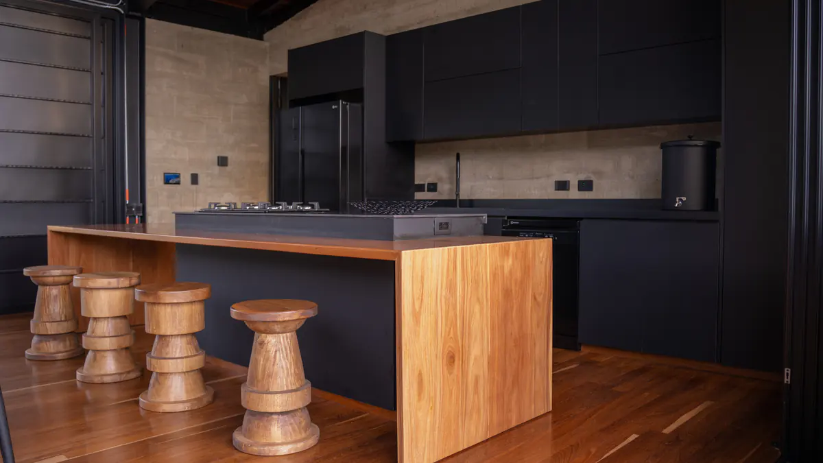 Cocina abierta en madera y tonos oscuros de Casa Audaz